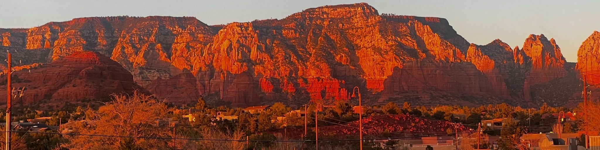 Red rock cliffs in Sedona, Arizona, glowing orange in the evening sun above the town